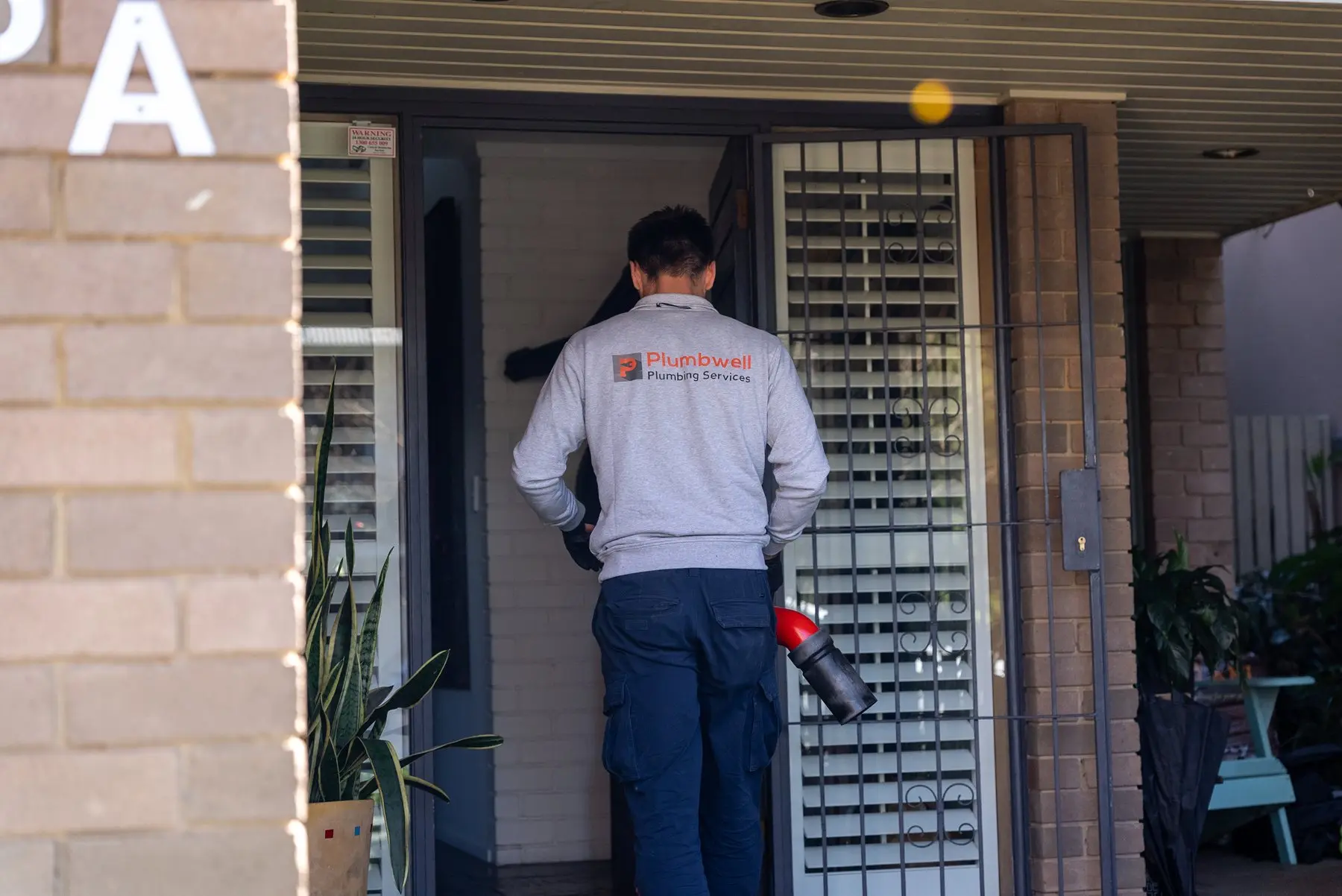 A Plumbwell emergency plumber at a front door