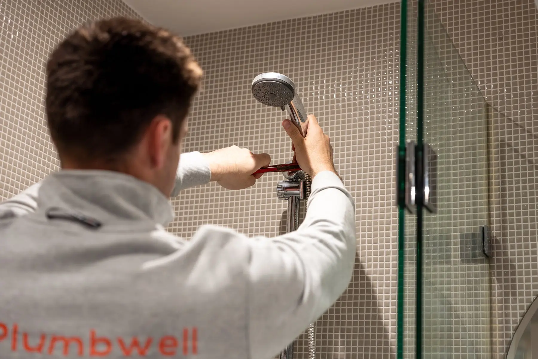 A Plumbwell plumber working on a shower drain