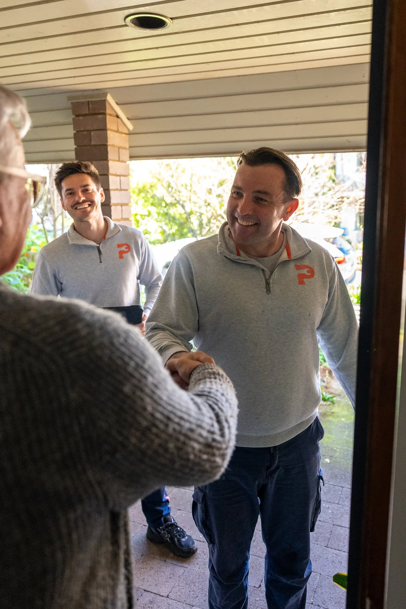 Plumbwell plumbers greeting a customer at the door